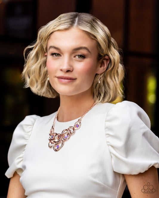 Warped rose gold frames asymmetrically curl around dainty white rhinestones and iridescent peach gem accents, interlocking into a contemporary statement piece below the collar. Features an adjustable clasp closure. Due to its prismatic palette, color may vary. Sold as one individual necklace. Includes one pair of matching earrings.